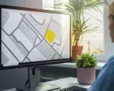 Kobieta analizuje na monitorze mapę działek, która przypomina wypis z rejestru gruntów. Jedna z działek jest podświetlona na żółto.
