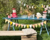 Une table bleue dressée pour une deco garden party à faire soi même, avec guirlandes, bonbons et fleurs.