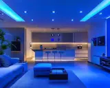 Nowoczesny salon z kuchnią, oświetlony niebieskim światłem. Porównanie lumenów różnych źródeł światła, od sufitowych po taśmy LED.
