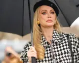 Mujer con boina negra y chaqueta a cuadros, sosteniendo un paraguas. Su maquillaje es un perfecto ejemplo de soft glam.