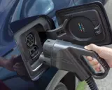 Mano insertando cargador en coche eléctrico. Averigua cuanto tarda en cargar un coche eléctrico en casa.