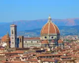 Vue panoramique de Florence avec le **dôme de Brunelleschi** dominant la ville, sous un ciel bleu clair.