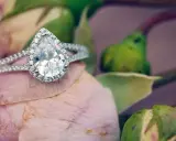 Un prezioso anello a goccia, simbolo di purezza e amore eterno, adagiato su un petalo di rosa.