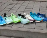 Różnorodne buty do biegania jakie wybrać, od jaskrawych po stonowane, ustawione na chodniku.