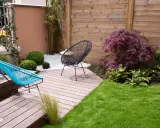 Aménagement d'un petit jardin de 100m2 : terrasse en bois, mobilier design, gazon et végétation luxuriante pour un espace détente moderne.