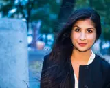Soraya Hashim ler mot kameran, hennes mörka hår blåser i vinden.