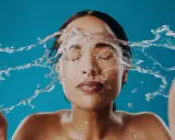 Una mujer se lava la cara con agua fría, sintiendo el frescor en su piel.