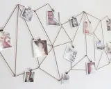 Sznurek tworzy geometryczny wzór na ścianie, na którym wiszą zdjęcia. Różnorodne tematy fotografii, od dzieci po krajobrazy, tworzą osobistą galerię.
