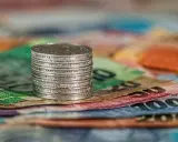 Stos monet na kolorowych banknotach. Czy to symbol najlepiej płatnych zawodów w Norwegii?