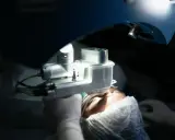 Chirurgiczna procedura z użyciem specjalistycznego sprzętu, który może być stosowany do zabiegów takich jak witrektomia. Pacjent w czepku i rękawiczkach.