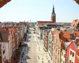 Widok z góry na urokliwą elbląg starówkę z kolorowymi kamieniczkami i wieżą kościelną w tle.