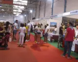 Gente en un evento de degustación de vinos, con stands de bodegas como "Coop Vinícola de Valdepeñas". El "túnel del vino Valdepeñas" se siente en el ambiente.
