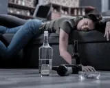 Kobieta leży nieprzytomna na kanapie, obok butelki i szklanka. Czy alkoholik może pić kontrolowanie? To pytanie pozostaje bez odpowiedzi.