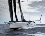 Le voilier Baltic 111 Raven fend les vagues, ses voiles noires gonflées par le vent.