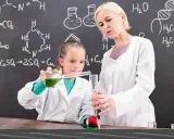 Nauczycielka chemii z pasją pokazuje uczennicy eksperyment. Ciekawe, ile zarabia nauczyciel chemii za taką pracę!