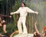 Bad Bunny's iconic bad bunny super bowl outfit, a white ensemble with a "64" on the sweatshirt, stands out against a backdrop of tall green stalks.
