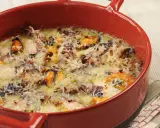 Un délicieux gratin de poisson et fruits de mer, gratiné au fromage, dans un plat rouge.