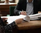 Kobieta i mężczyzna przy biurku przeglądają dokumenty. Sprawa alimentów, gdy nie płaci alimentów kiedy do komornika, wymaga analizy papierów.
