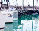 Des voiliers modernes, prêts à prendre la mer, sont amarrés dans un port. Leurs proues blanches et leurs ancres visibles rappellent le cale bateau.