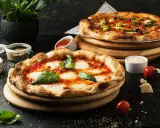 Dwie pyszne pizze, jedna margherita, druga z dodatkami. Obok sosy i pomidorki, idealne dodatki do pizzy.