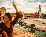 Flamenco-Tänzerin vor der Plaza de España in Sevilla, Spanien. Ein Wasserfall sprudelt im Hintergrund.