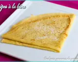 Crêpes à la bière, dorées et saupoudrées de sucre, sur une assiette blanche. Un délice gourmand !