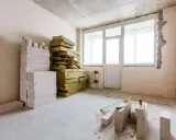 Materiały budowlane: pustaki i wełna mineralna, gotowe do ocieplenia od wewnątrz. Narzędzia budowlane leżą na podłodze.