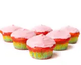 Bunte Muffins mit Lebensmittelfarbe und rosa Zuckerguss, die wie ein Regenbogen aussehen.