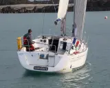 Un voilier Dufour 325 Grand Large navigue, un homme à la barre. Avis de navigation en mer.