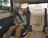 Niño sonriente en una silla de coche grupo 3 edad, viajando seguro y cómodo en el asiento trasero de un vehículo.