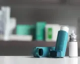 Zwei Inhalatoren, einer davon mit einem silbernen Behälter, liegen auf einer weißen Oberfläche. Sie sind wichtige Hilfsmittel bei der Behandlung von COPD, wo Cortison oft eine Rolle spielt.