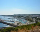 Vista panoramica del porto turistico di Santa Maria di Leuca, in provincia di Lecce, con numerose barche ormeggiate e la città bianca sullo sfondo.