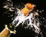 Le bouchon d'une bouteille de champagne s'envole dans un jet d'eau et de bulles, un moment de joie pour sabler le champagne.