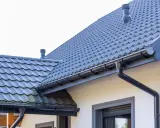 Szary dach z dachówki ceramicznej, idealny do obliczenia dachówka ceramiczna cena za m2. System rynnowy odprowadza wodę.