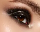 Ojo con un espectacular maquillaje ahumado marrón con brillos intensos y pestañas largas.