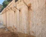 Muros pantalla de contención con anclajes metálicos, mostrando la textura rugosa de la roca y la tierra.