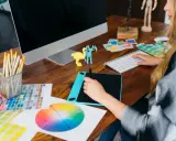 Kreatywna przestrzeń: graficzka przy biurku z tabletem graficznym, próbkami kolorów i komputerem. Idealne miejsce do tworzenia sitodruk grafika.