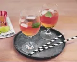 Zwei Gläser Rosato Spritz mit Eis und Minze, dazu Limettenspalten und ein Messbecher. Perfekt für einen sommerlichen Genuss.