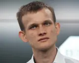 Vitalik Buterin, twórca Ethereum, z niebieskimi oczami i krótkimi włosami, w białej koszuli.