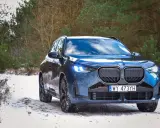 Niebieskie, nowe BMW X3 na ośnieżonej drodze w lesie. Zimowe opony gotowe na wyzwania.