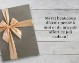 Un cadeau gris avec un ruban doré, accompagné d'un message : "Merci beaucoup d'avoir pensé à moi et de m'avoir offert ce joli cadeau !