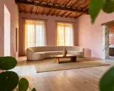 Salon aux murs roses, canapé courbe, table basse en bois et tapis en jute. Une ambiance douce et harmonieuse pour une maison feng shui.