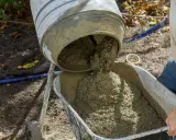 Beton B25 wylewa się z betoniarki do taczki. Proporcje na łopaty są kluczowe dla uzyskania odpowiedniej konsystencji.