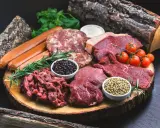 Mięso wołowe, kiełbaski, kotlety i przyprawy na desce. Idealne składniki dla diety carnivore.