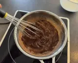 Préparation d'une recette ganache chocolat : du chocolat fondu est fouetté dans une casserole sur une plaque chauffante.