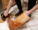 Domowy sposób na impregnację butów: ręka zanurza drewnianą łyżkę w garnuszku z preparatem, by nałożyć go na skórzany but.