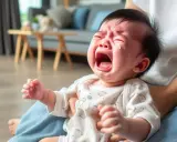 Un bebé enfadado llora desconsoladamente, con lágrimas en los ojos y la boca abierta.