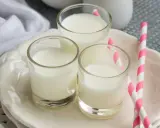Trzy szklanki mleka, idealne do sprawdzenia, ile białka ma mleko. Różowe słomki dodają uroku.