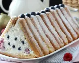 Délicieuse recette buche fruits rouges : un gâteau léger garni de crème et de baies, entouré de biscuits à la cuillère saupoudrés de sucre glace.