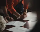 Manos de testigos boda civil firmando documentos importantes.